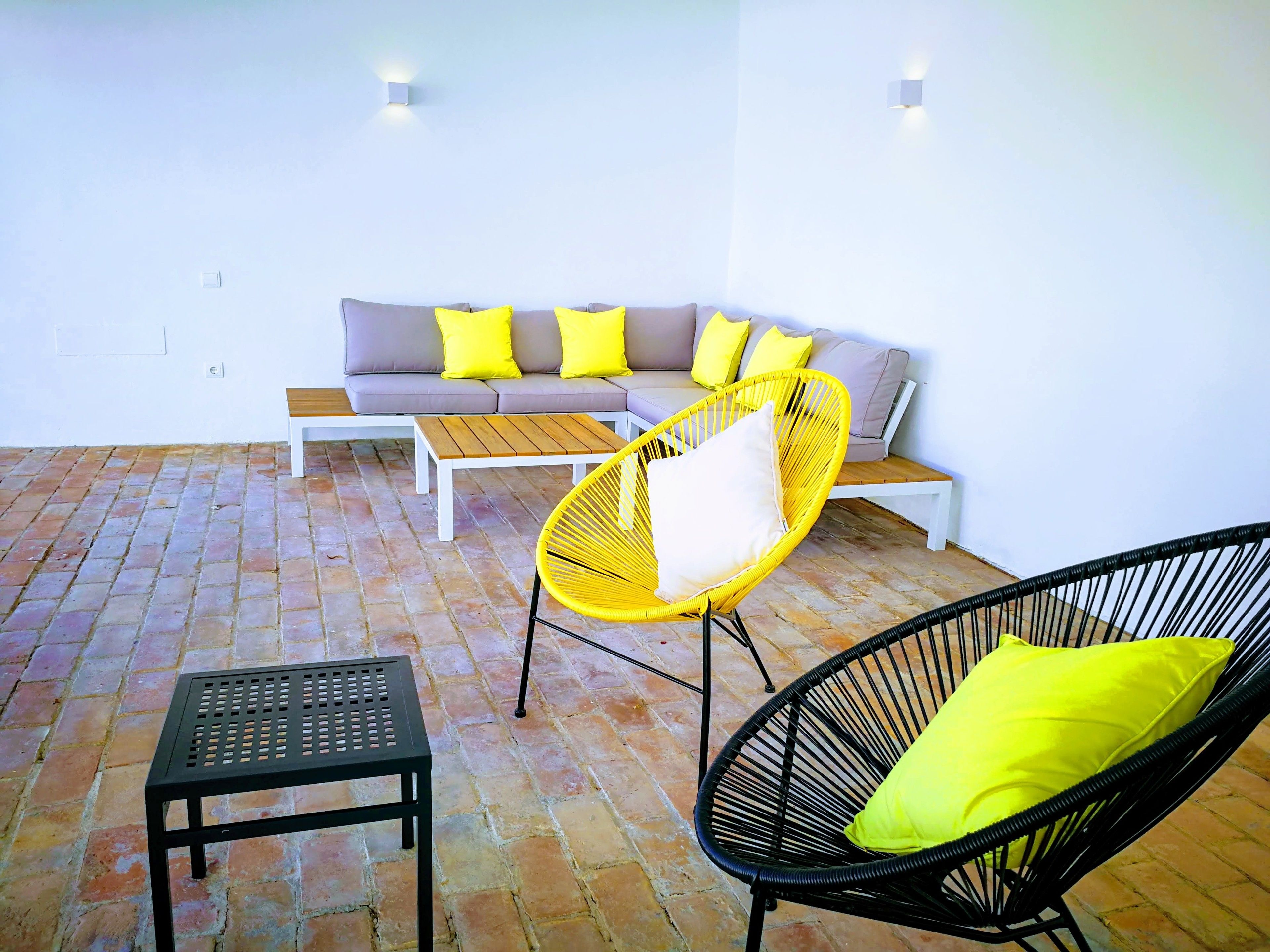 A patio area with a sofa, two chairs, a small table, and a bench.