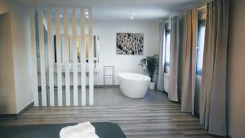Un baño moderno con una bañera independiente, un espejo grande y una planta en maceta.