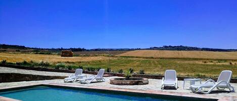 A swimming pool with lounge chairs and a view of a hilly landscape.