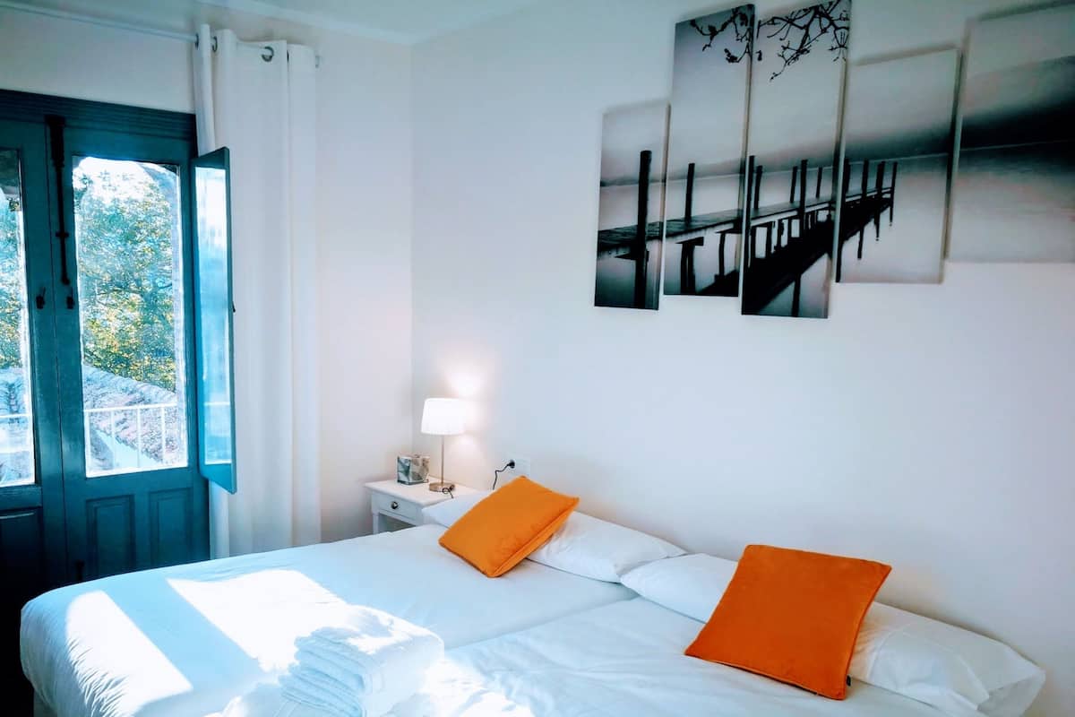 A hotel room with a bed, a nightstand with a lamp, and a window with curtains.