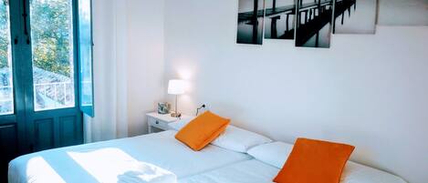A hotel room with a bed, a nightstand with a lamp, and a window with curtains.