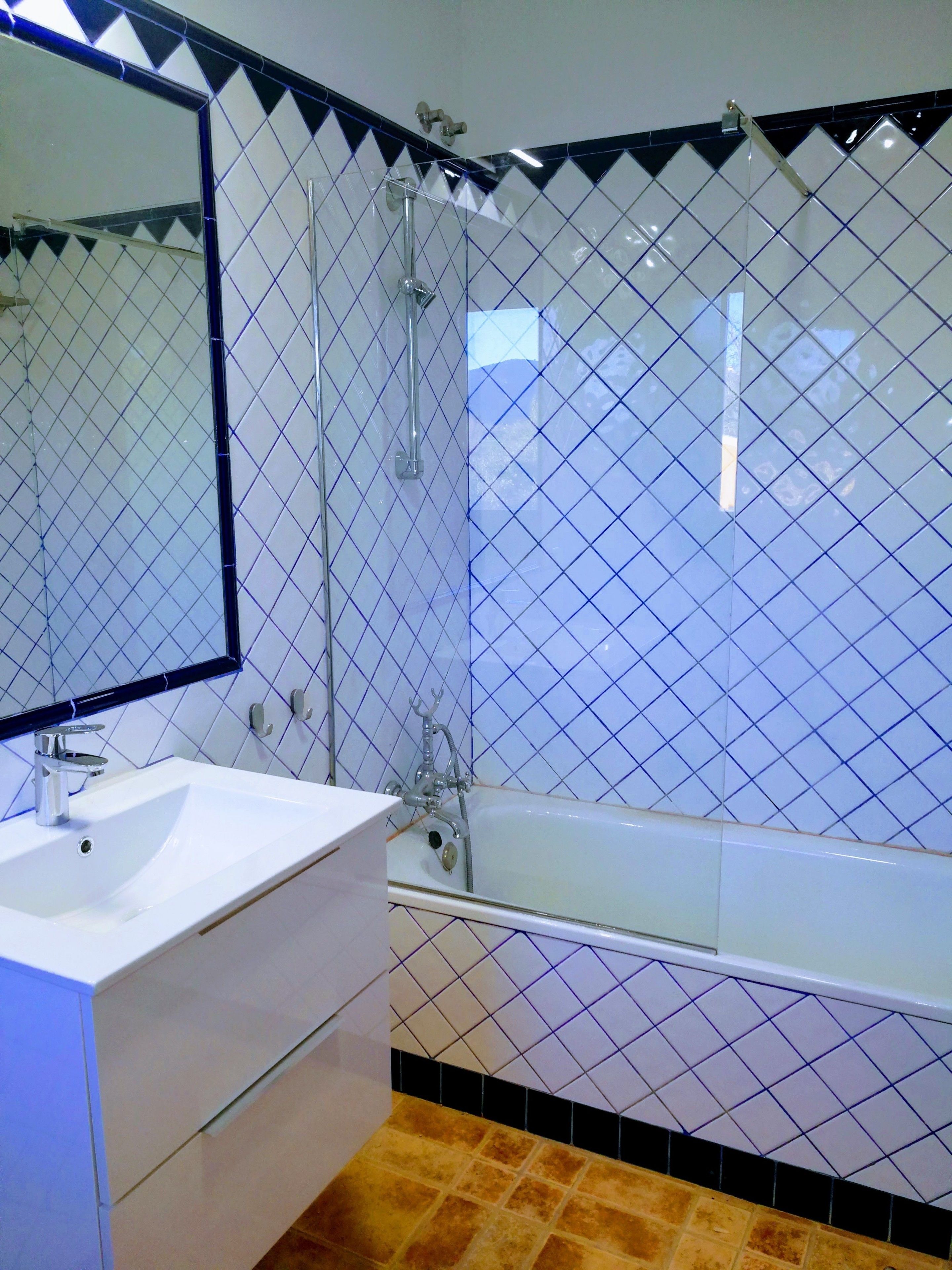 Un baño con lavamanos blanco, espejo, cabina de ducha de vidrio y bañera.