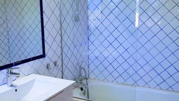 Un baño con lavamanos blanco, espejo, cabina de ducha de vidrio y bañera.