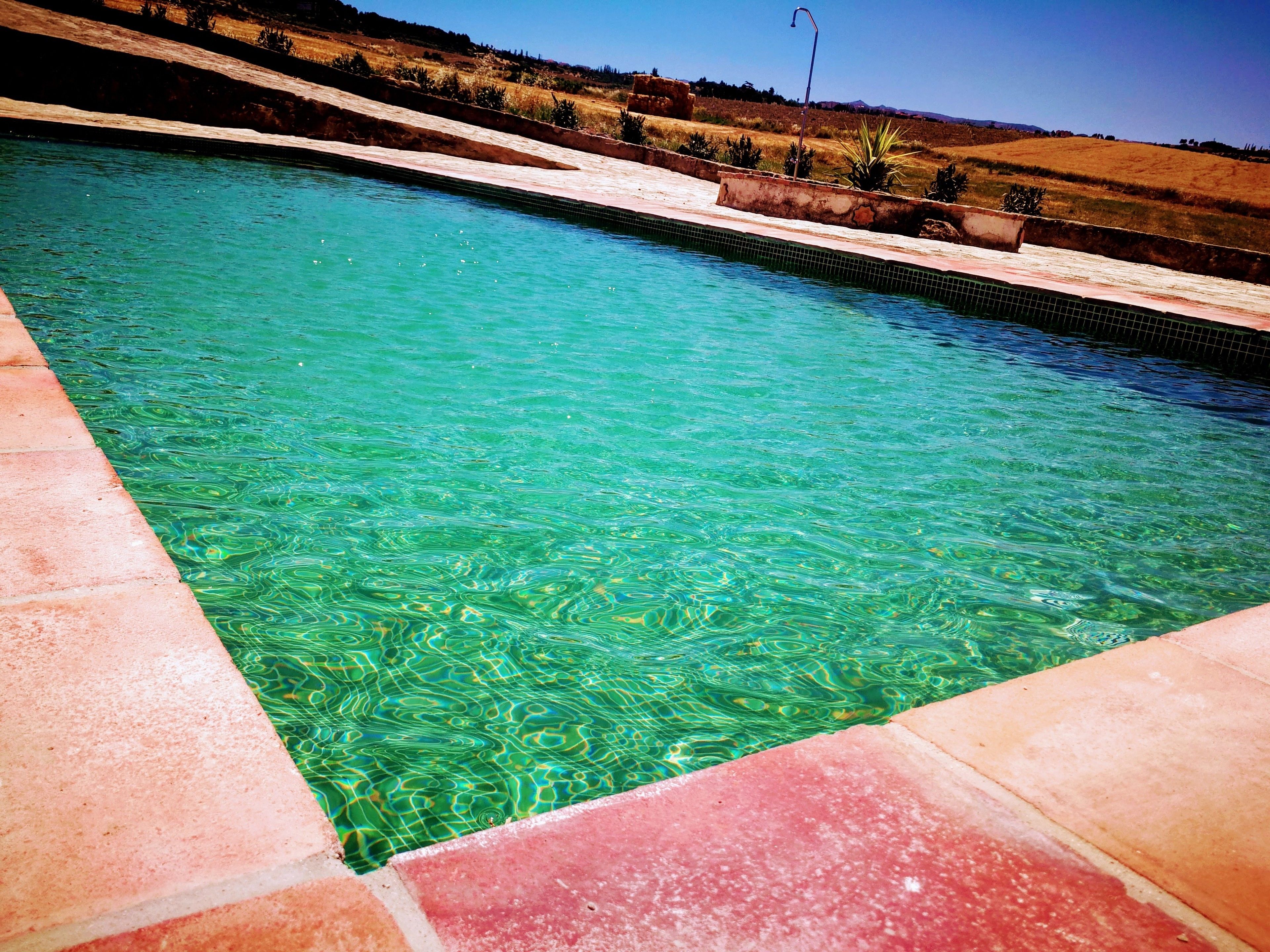 Una piscina cristalina con borde de azulejos y vistas a un paisaje montañoso al fondo.