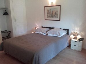 A bedroom with a bed, a nightstand, a lamp, and a framed picture on the wall. - Prato Plage (Pernes-les-Fontaines)