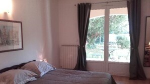 Un dormitorio con cama, ventana con cortinas y radiador.