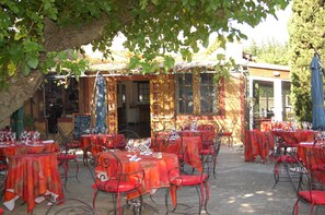 An outdoor café with tables and chairs, a chalkboard menu, and a statue. - Prato Plage (Pernes-les-Fontaines)