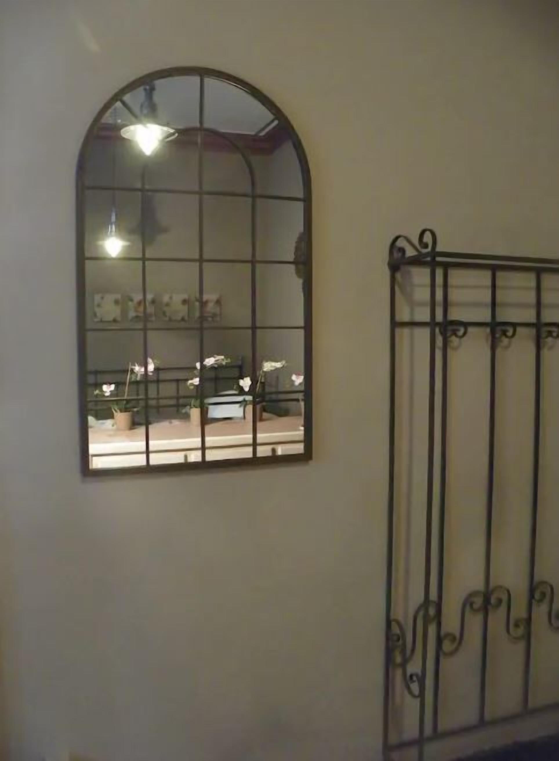 Ein Zimmer mit einem großen Bogenfenster, einem Metallgeländer und einem Deckenventilator.