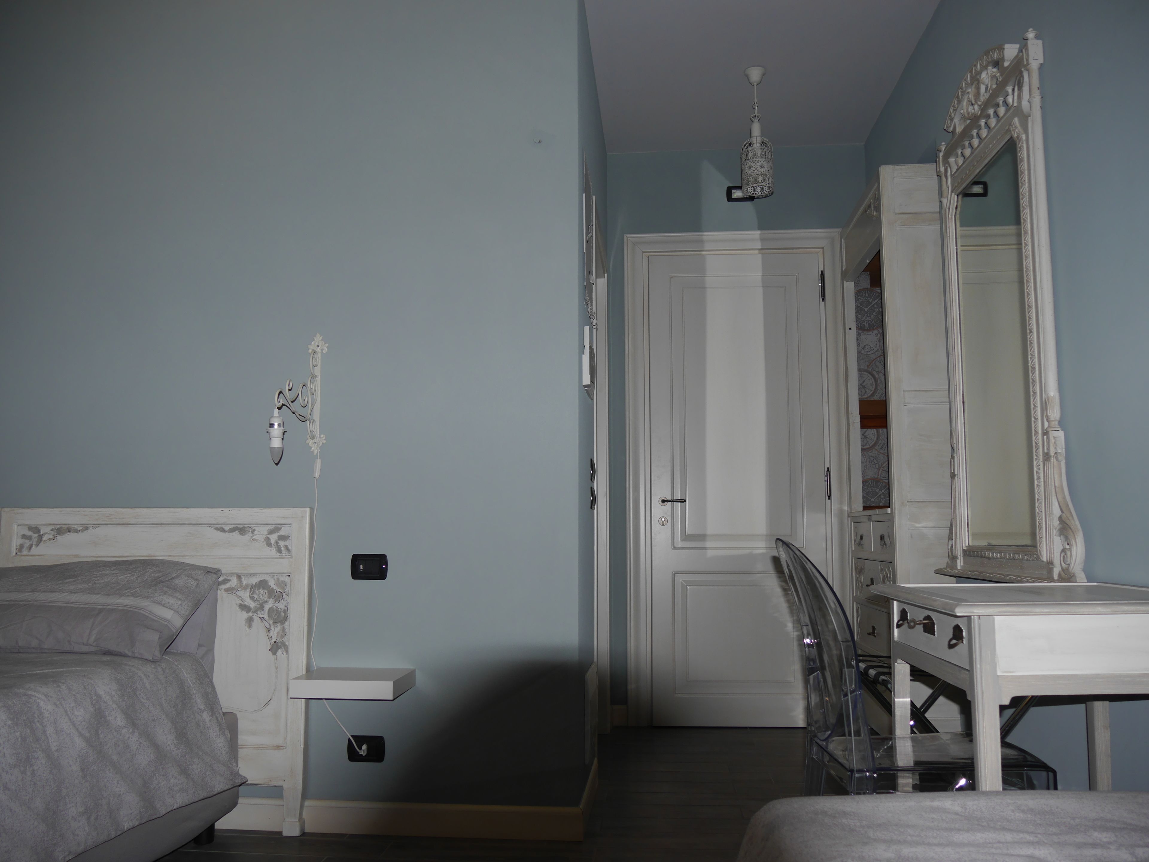 Una camera da letto con un letto, un comodino, uno specchio e un armadio.