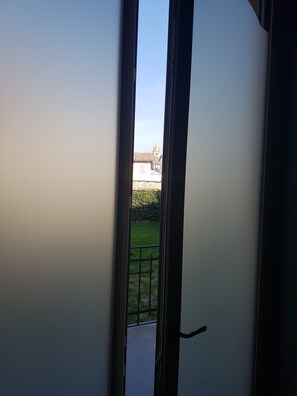 A view through a door opening to a courtyard with a building in the background. - B&B L'Ortodellerose (Alba)