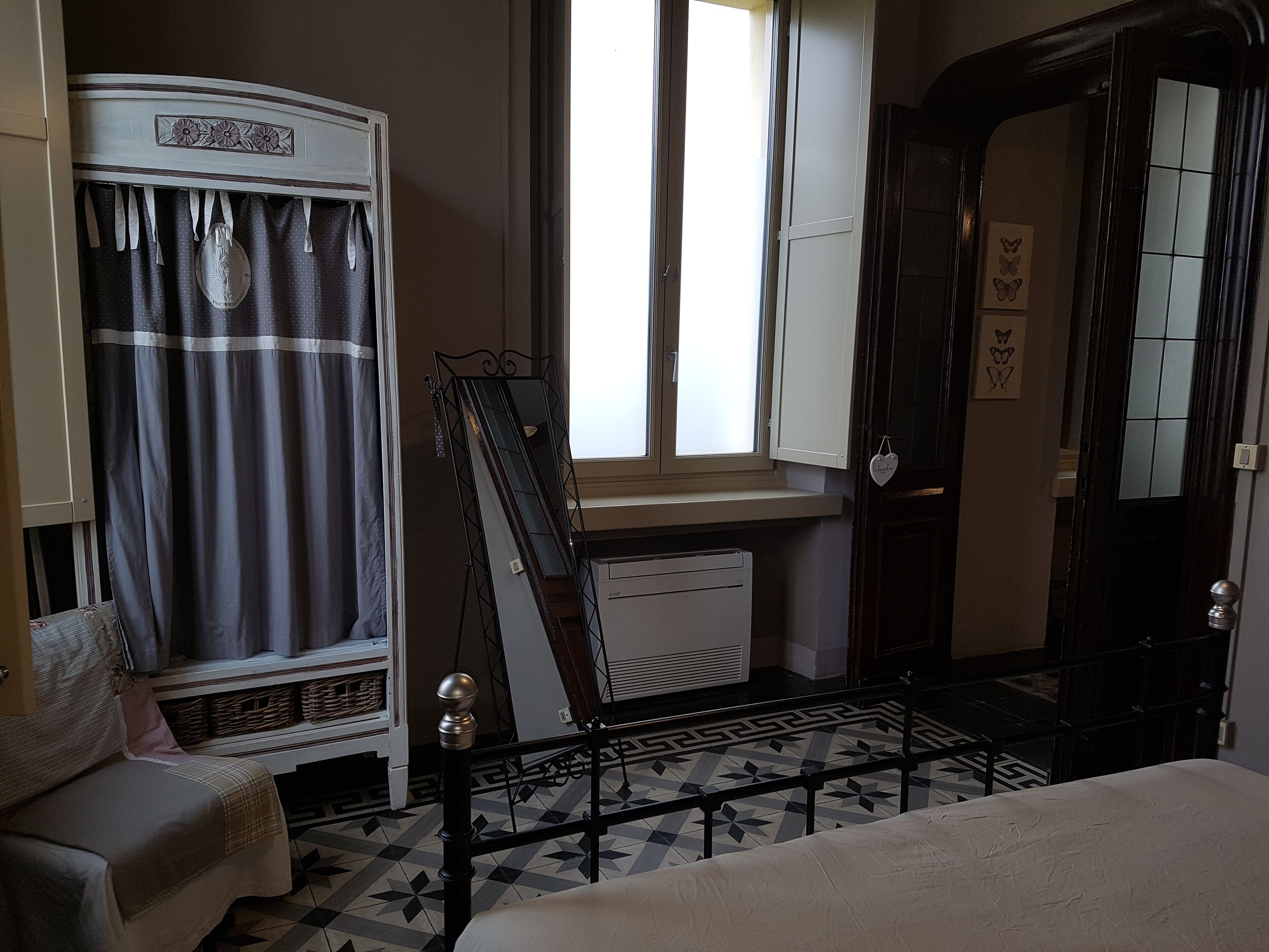 A room with a bed, a wardrobe, a window, and a radiator.