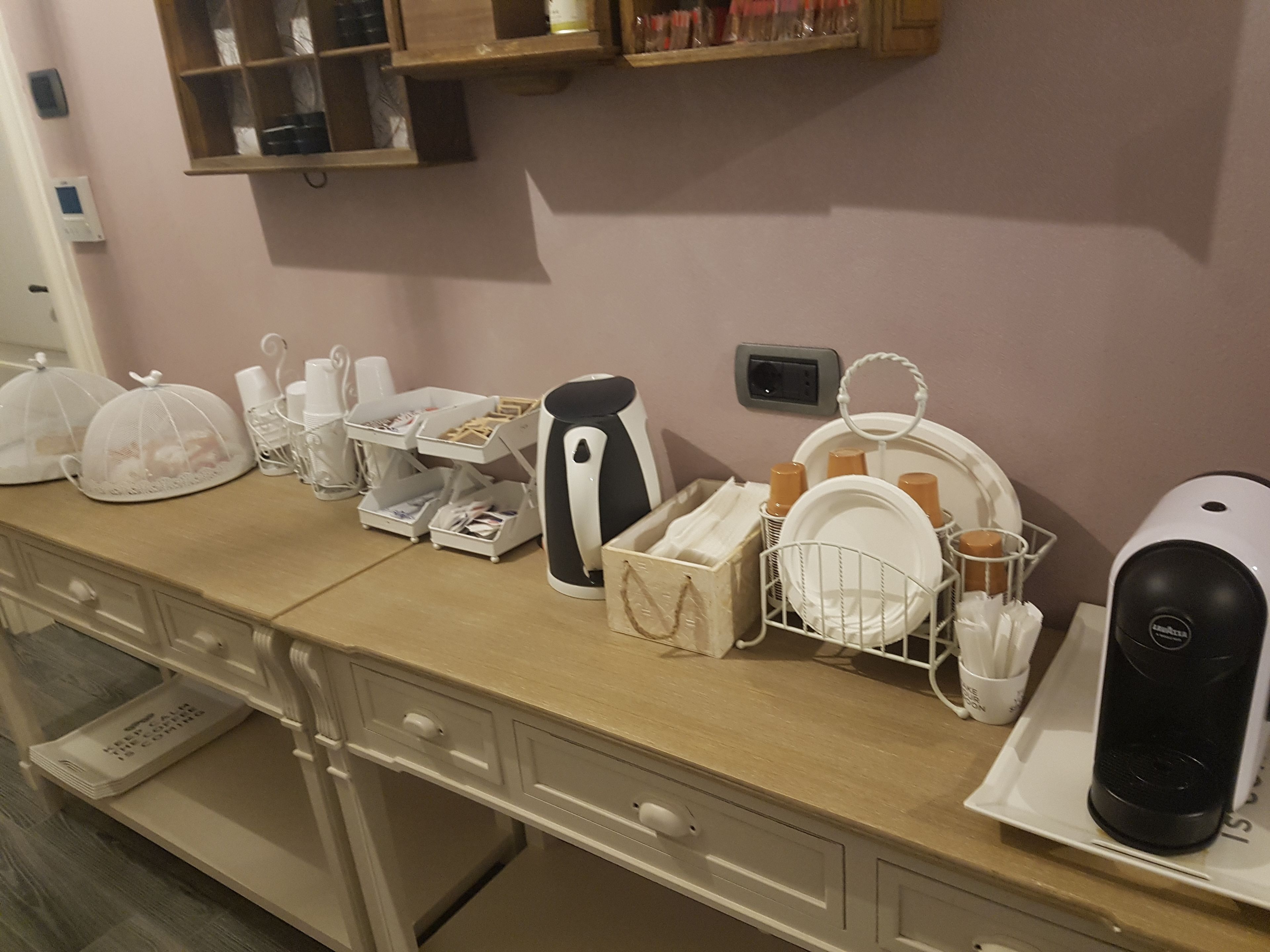 Un plan de travail de cuisine équipé de divers appareils et ustensiles, notamment une machine à café, une bouilloire et des égouttoirs à vaisselle.