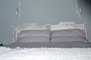 A bed with a white headboard, gray bedding, and a white textured blanket. - B&B L'Ortodellerose (Alba)
