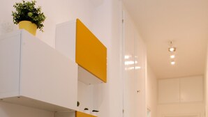 A hallway with a white and yellow wall unit, a door, and a tiled floor. - City Central (Salerno)