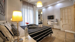 A hotel room with a bed, bedside table, lamp, and a TV. - City Central (Salerno)