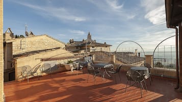 Una terraza con mesa y sillas, con vistas a un edificio histórico con una torre.