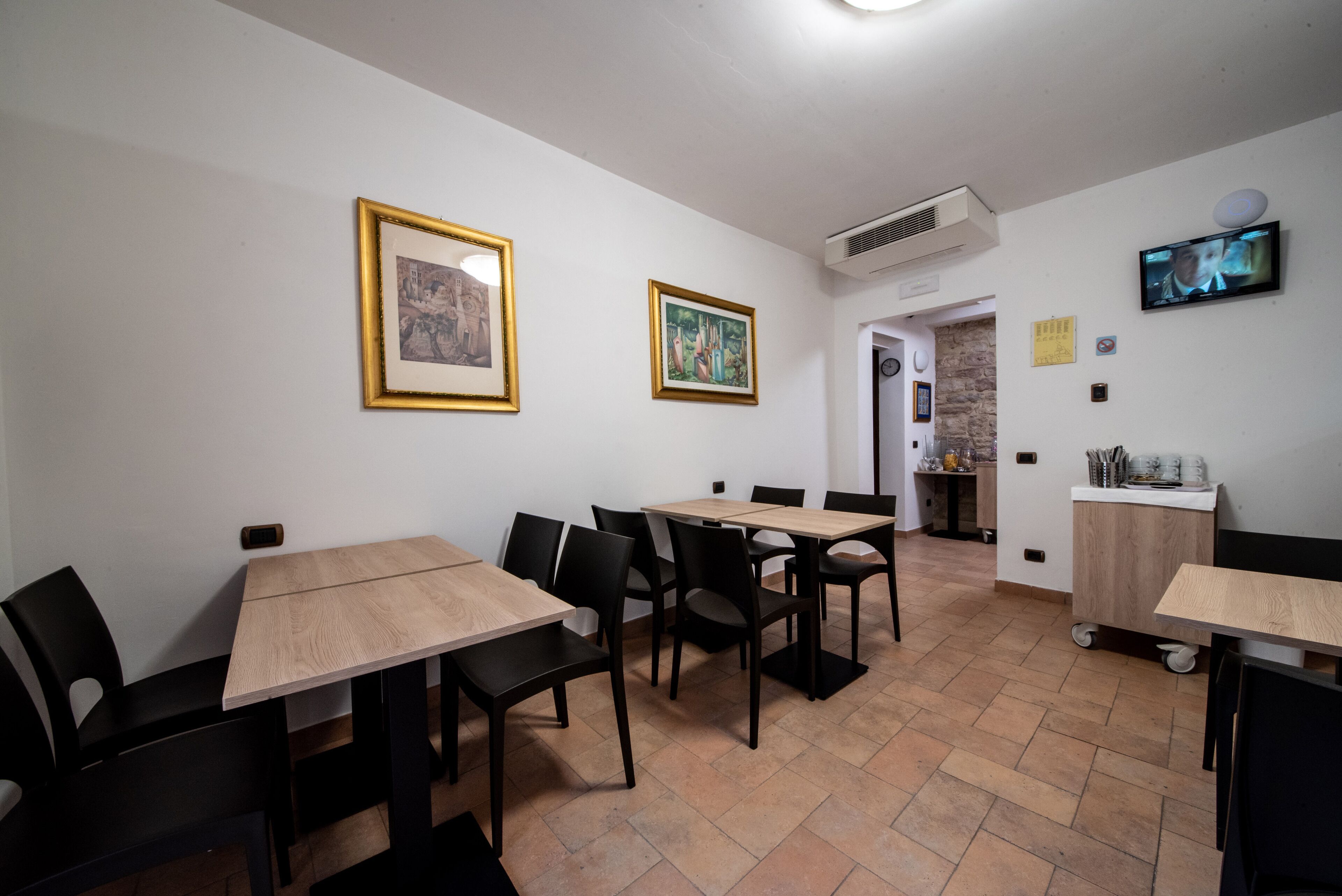 Un comedor con mesas y sillas, obras de arte en las paredes y un televisor.