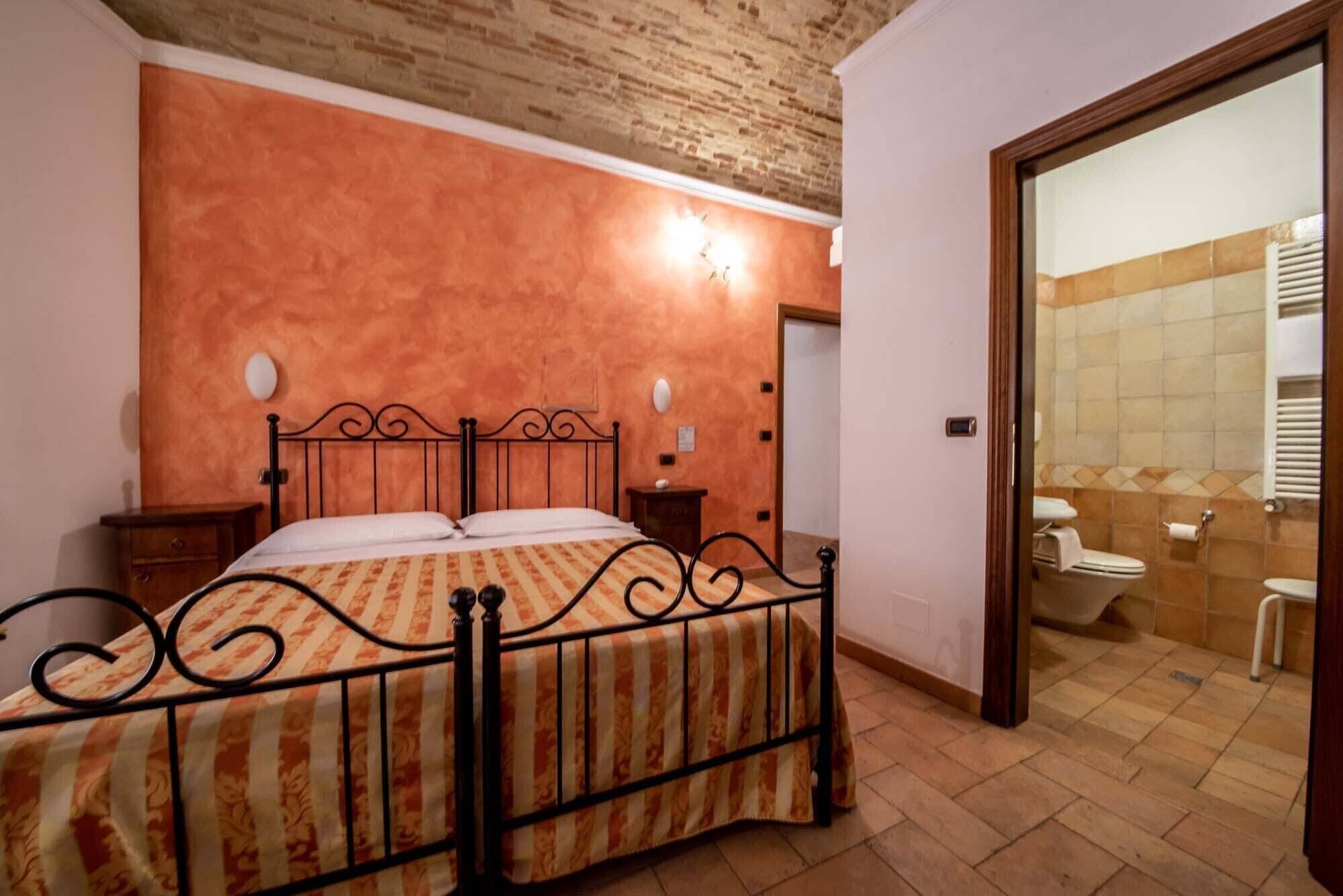 A bedroom with a bed, bedside tables, and a bathroom visible through an open door.