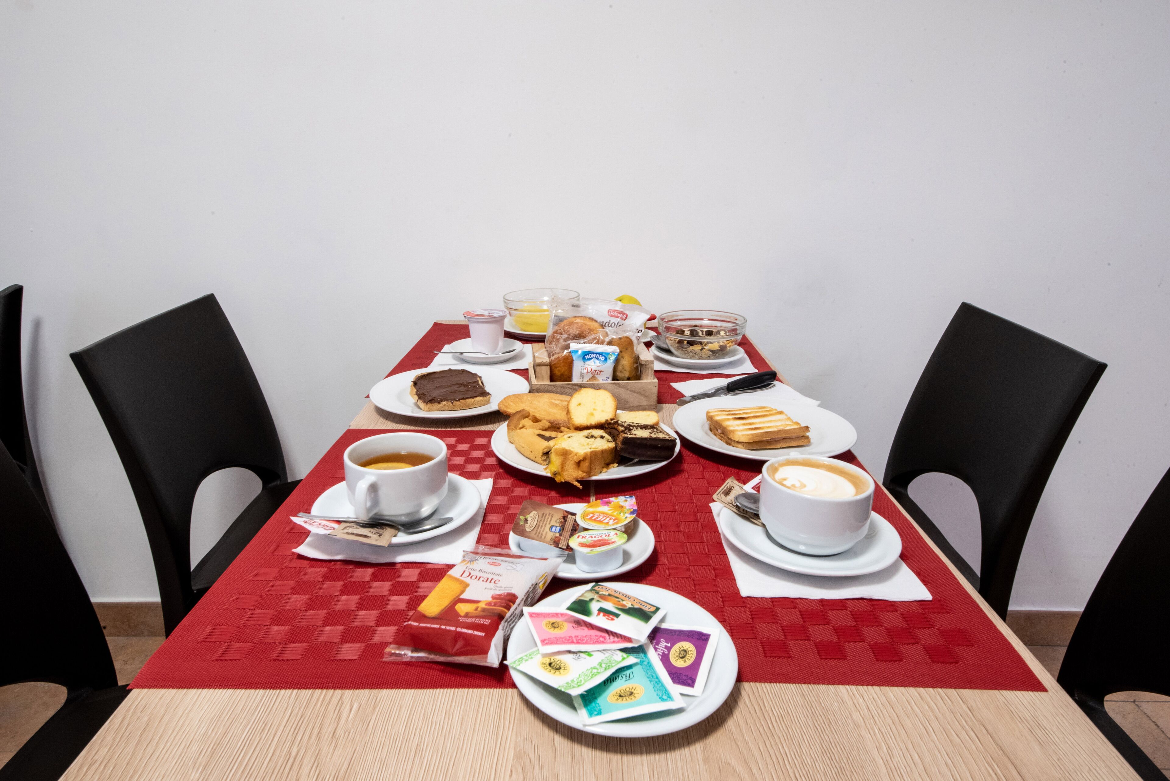 A dining table set with various breakfast items including pastries, sandwiches, and beverages.