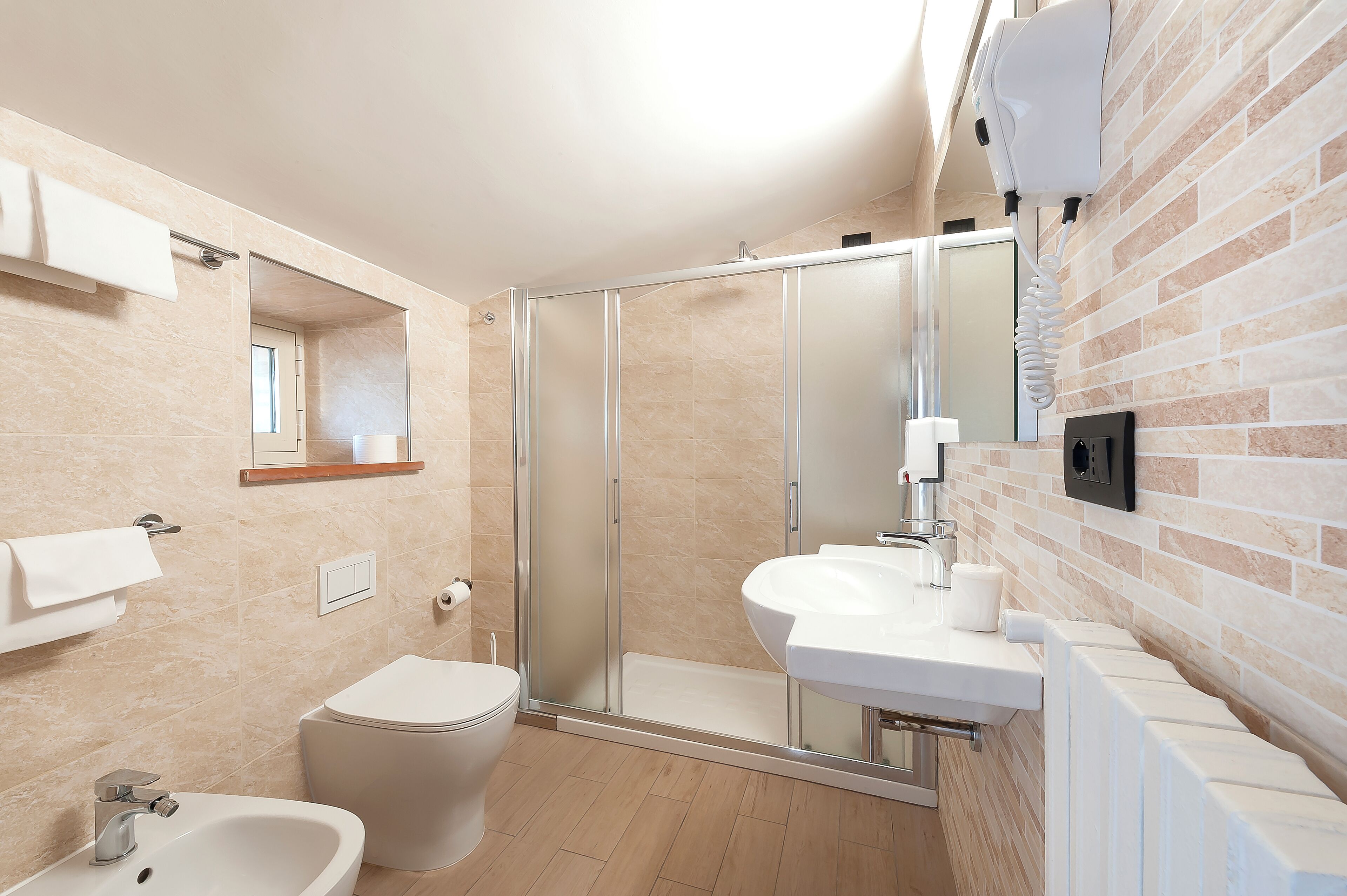 Un baño moderno con ducha envuelta en vidrio, un lavamanos blanco y un inodoro.