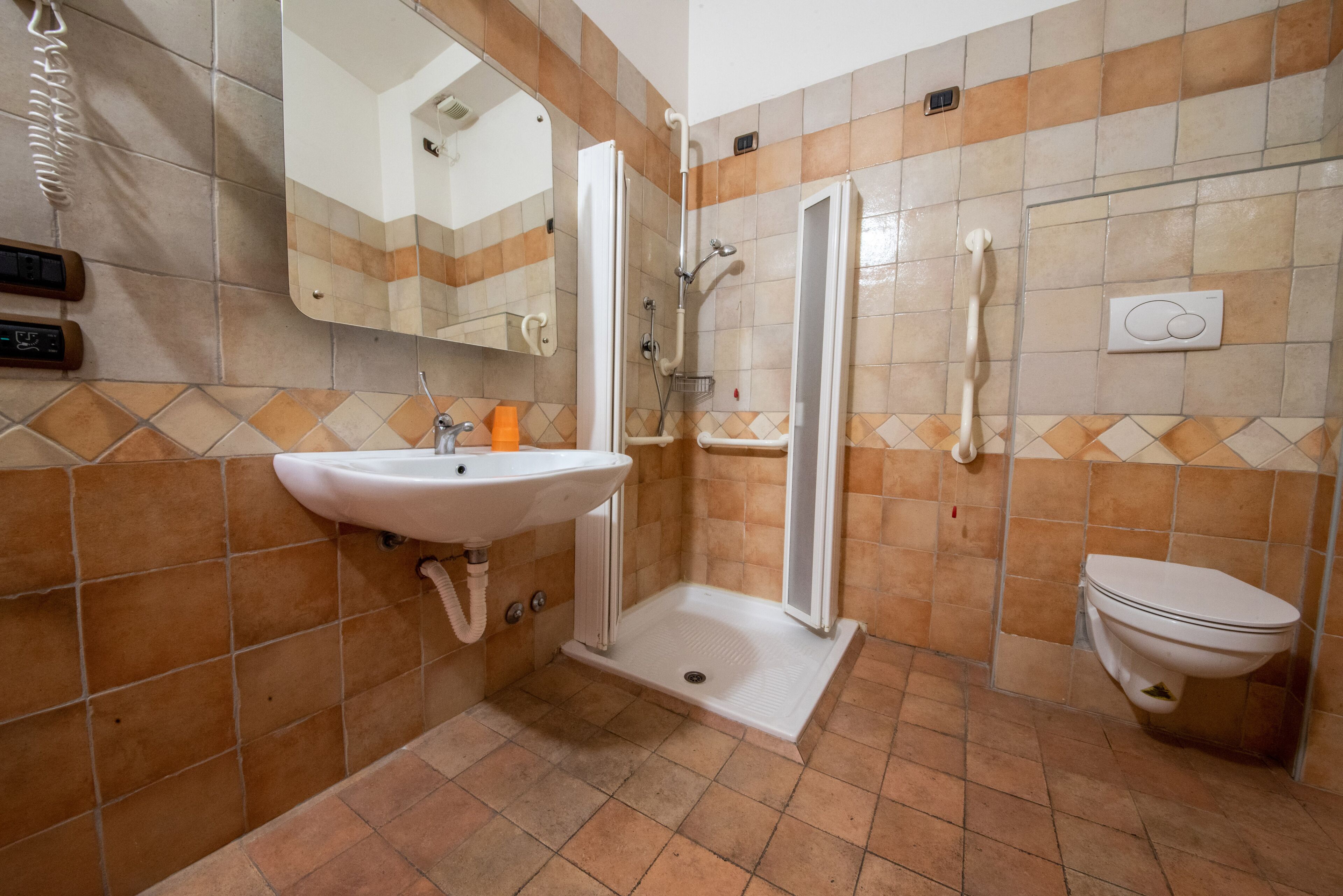 A bathroom with a sink, toilet, shower, and a mirror.