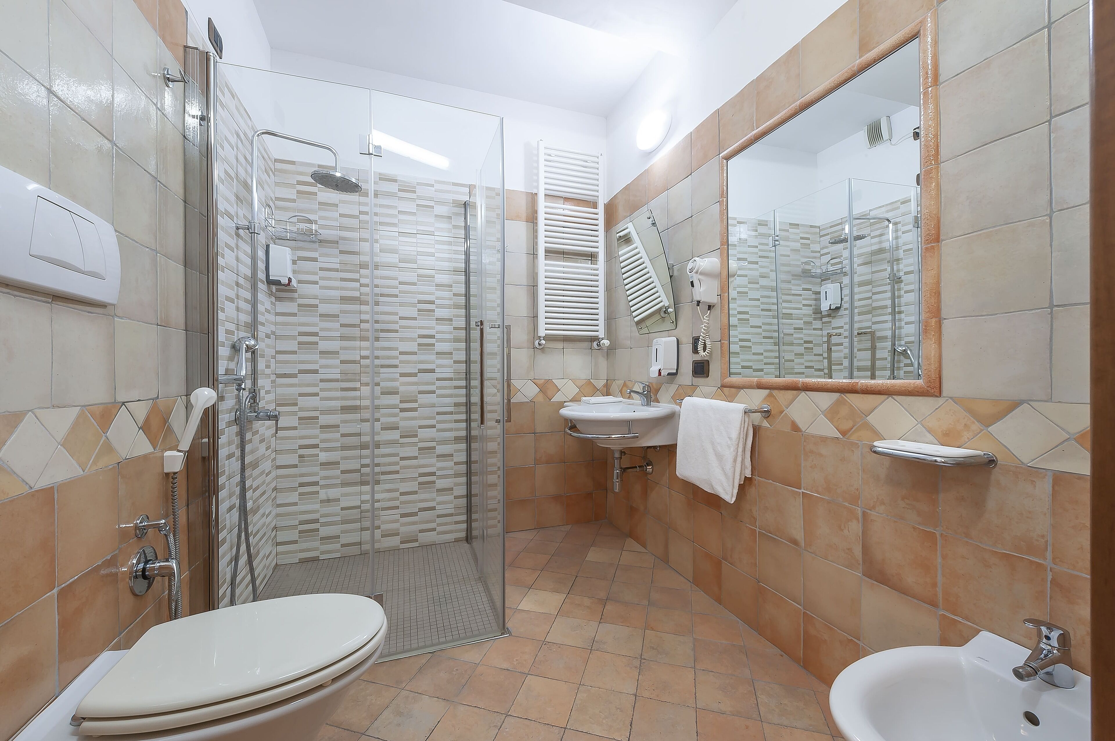 Een moderne badkamer met een douchecabine van glas, een toilet, een wastafel en een spiegel.