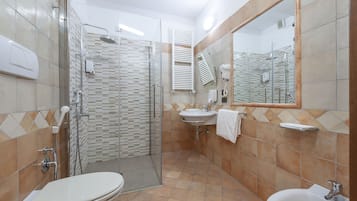 Een moderne badkamer met een douchecabine van glas, een toilet, een wastafel en een spiegel.