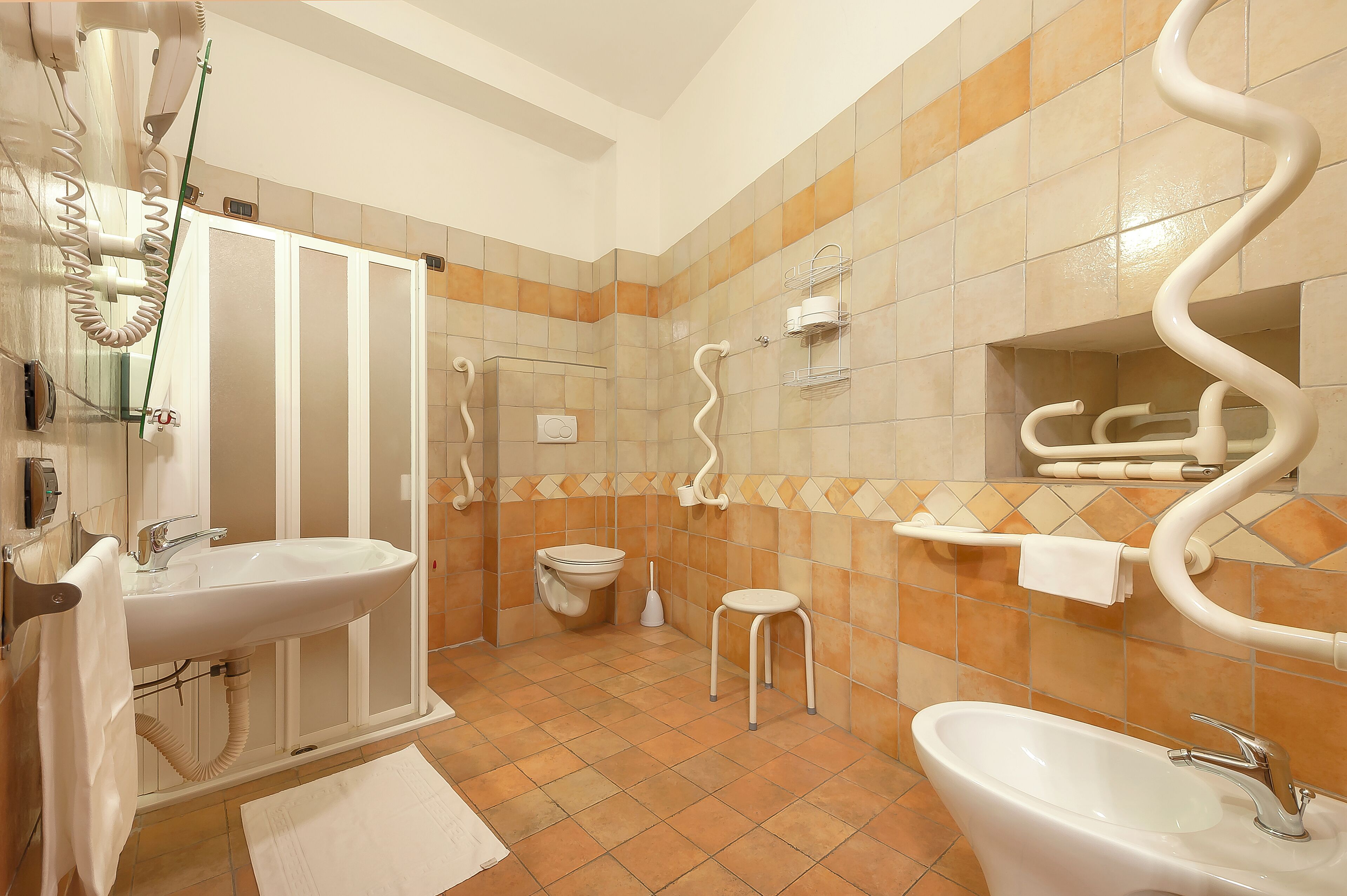 Un baño con dos lavamanos, un inodoro, una ducha y un perchero para toallas.