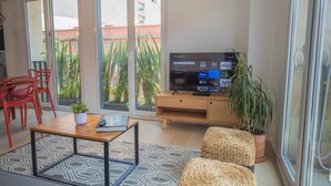 Un salon moderne avec un téléviseur, des fauteuils rouges, une table basse en bois et une plante en pot.