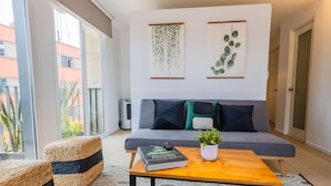 Un salon moderne avec un canapé gris, une table basse en bois et une plante en pot.