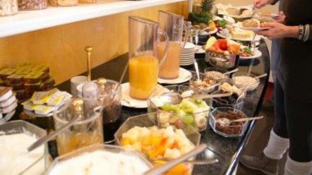 A buffet with various food items and beverages, including fruits, salads, and a pitcher of orange juice. - Hotel AM ELBUFER (Hamburg)