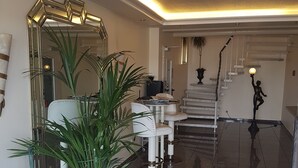 A modern lobby with a marble floor, a red carpet, a large mirror, a staircase, and a statue. - Hotel AM ELBUFER (Hamburg)