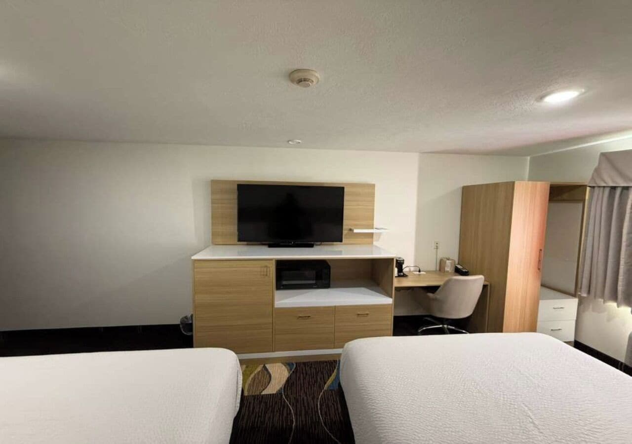 A hotel room with two beds, a TV, a desk, and a wardrobe.