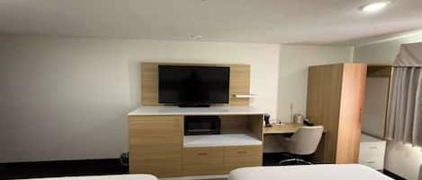 A hotel room with two beds, a TV, a desk, and a wardrobe.