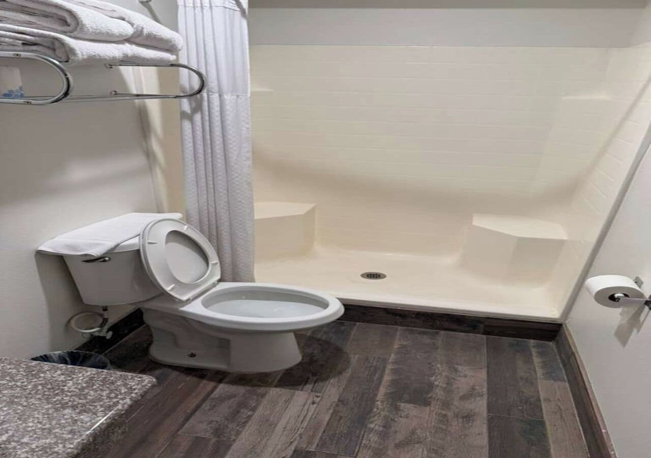Une salle de bain équipée de toilettes, d’une douche et d’un porte-serviettes.