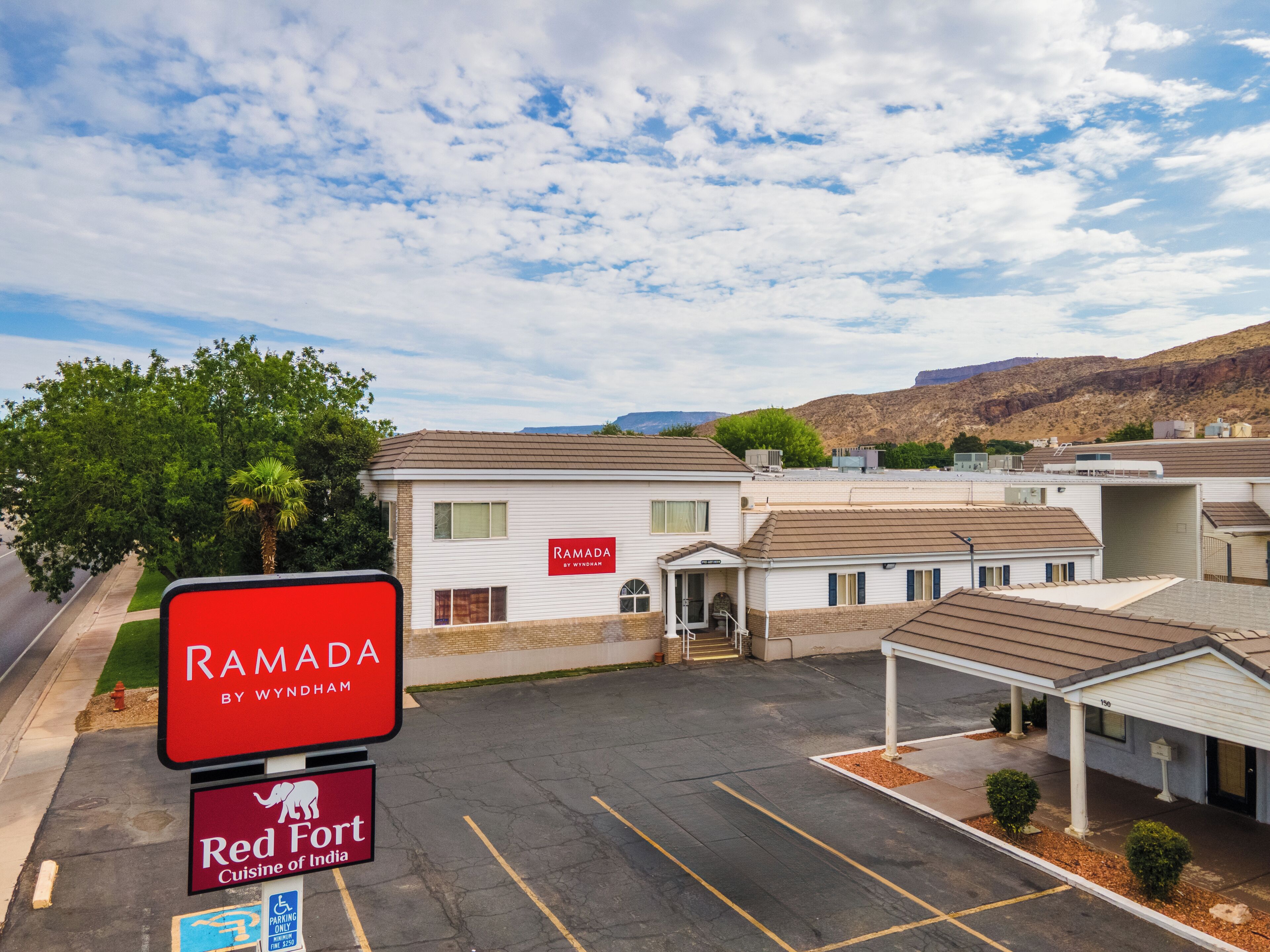 Een parkeerplaats met een bord voor Ramada by Wyndham en Red Fort Cuisine of India.
