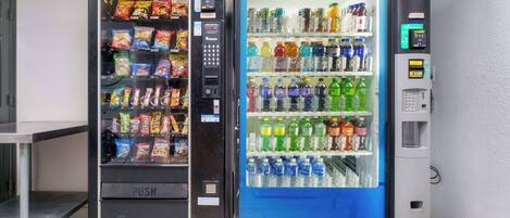Dos máquinas expendedoras, una con la etiqueta 'PUSH' y la otra 'AQUAFINA', con diferentes aperitivos y bebidas en su interior.