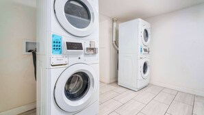 A laundry room with two stacked front-loading washing machines and a dryer.