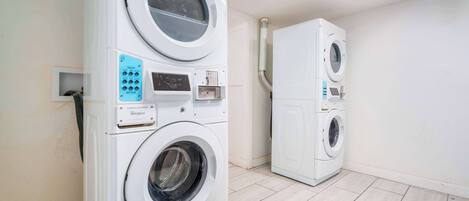 A laundry room with two stacked front-loading washing machines and a dryer.