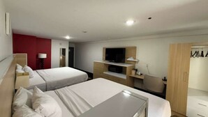 A hotel room with two beds, a TV, a desk, and a wardrobe.