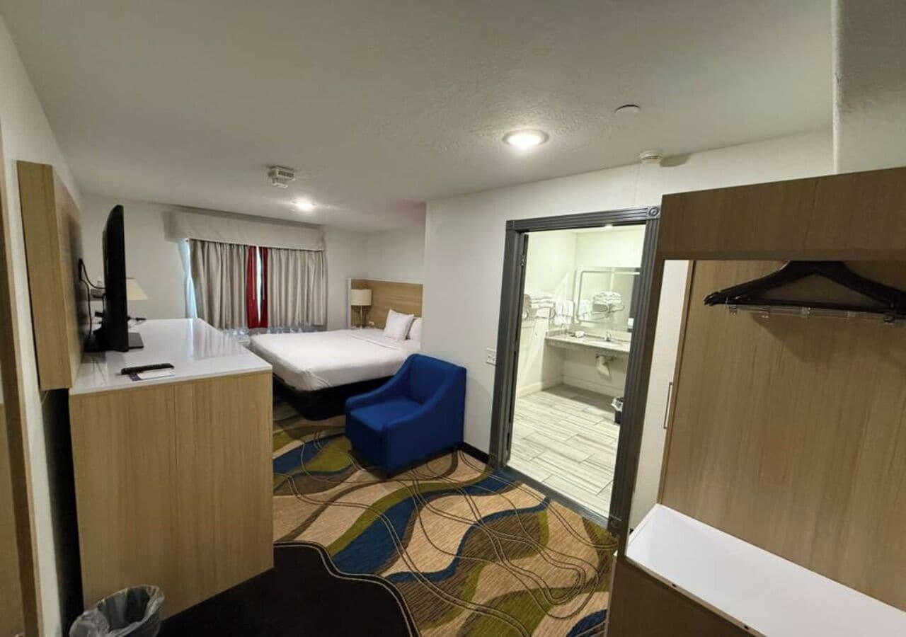 Habitación de hotel con cama, escritorio, silla, baño y vista a la ciudad.