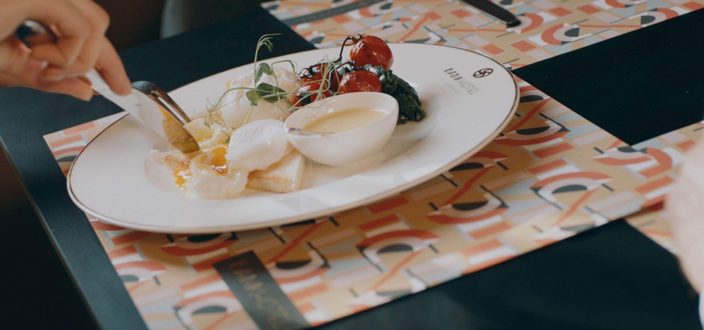 A plate with food on a table with a patterned tablecloth.