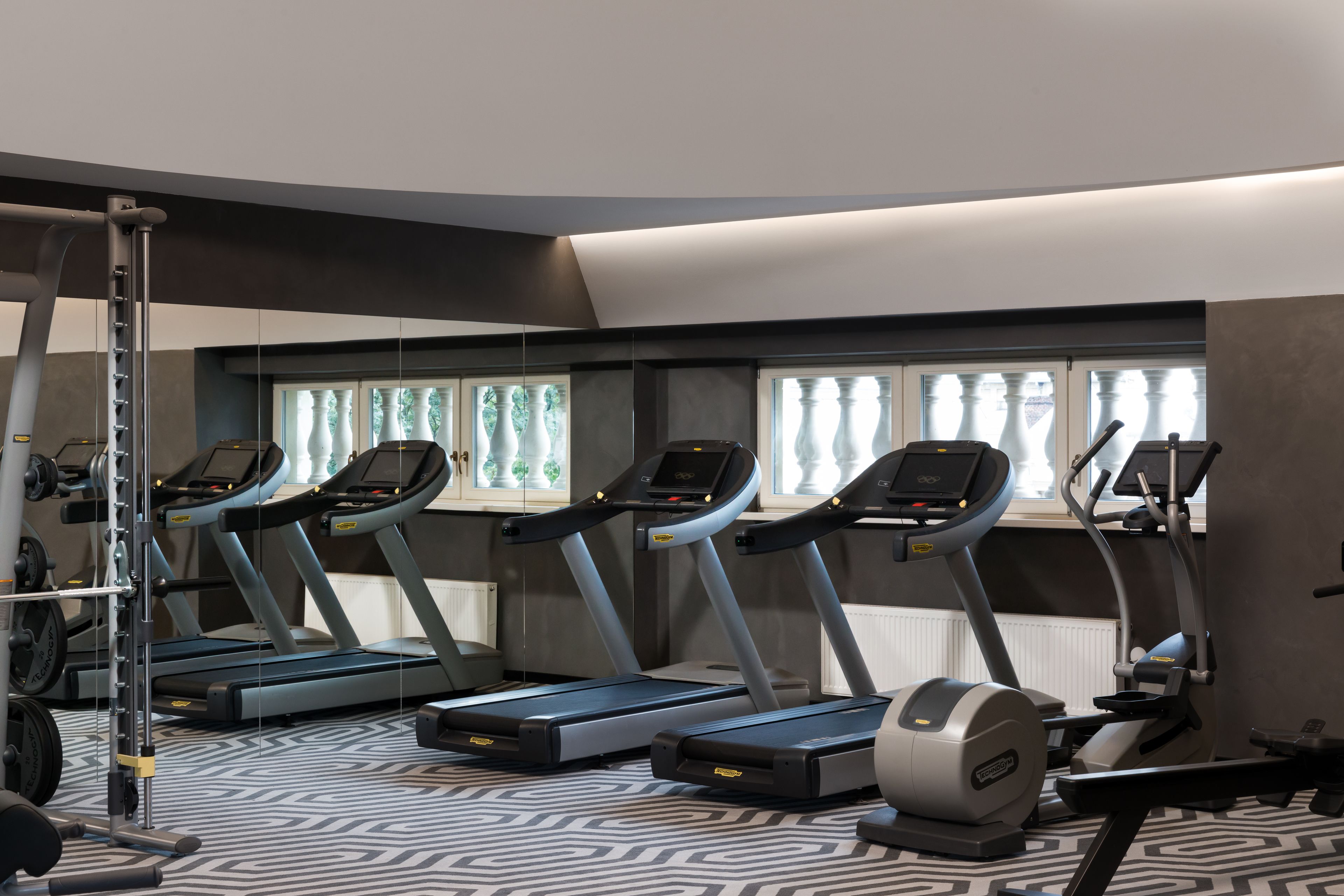 Un gimnasio con cintas de correr, una banca de pesas y una máquina de remo.
