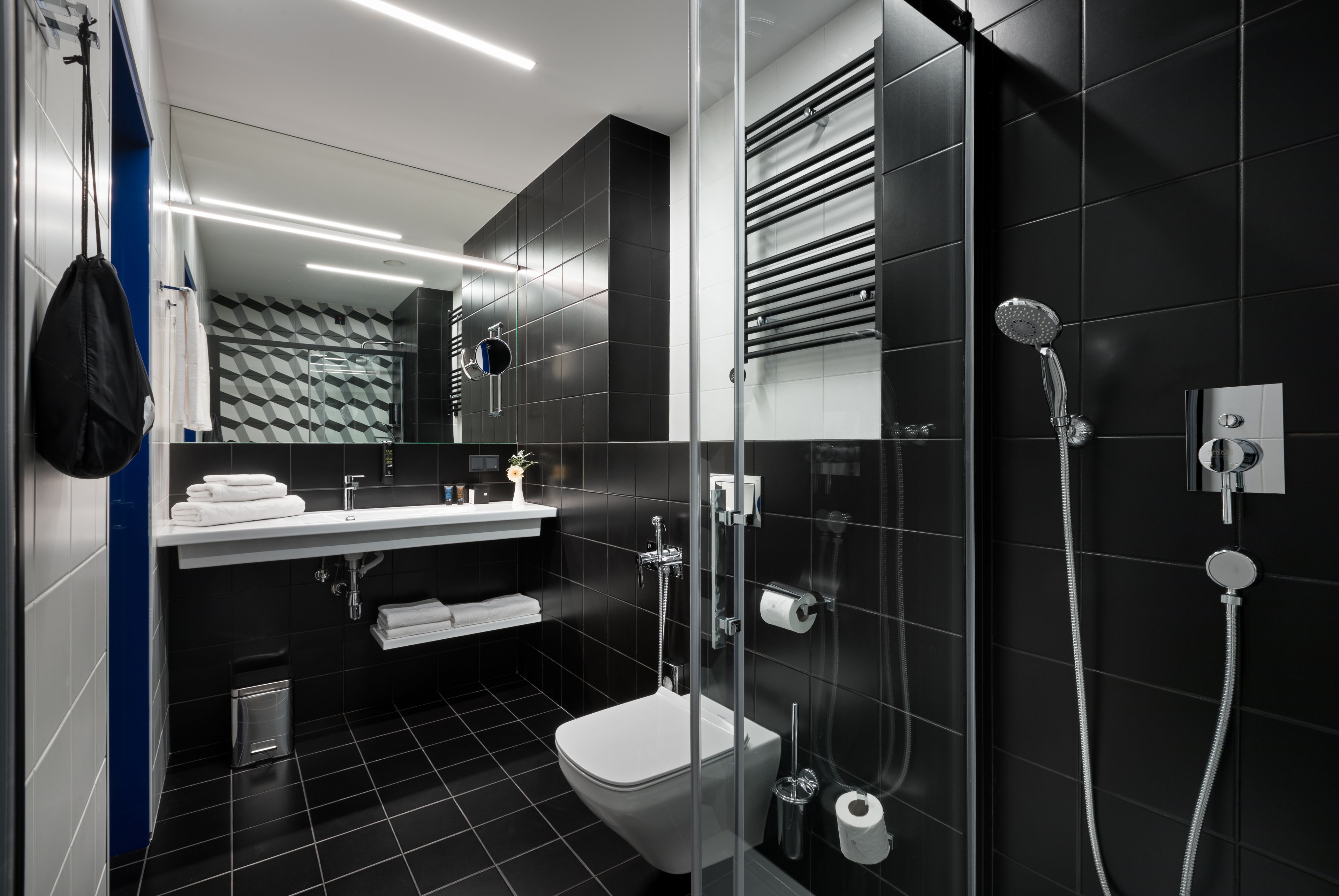 A modern bathroom with a glass-enclosed shower, a white toilet, and a sink with a towel rack.