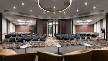 A conference room with rows of chairs, tables, and a circular light fixture on the ceiling.