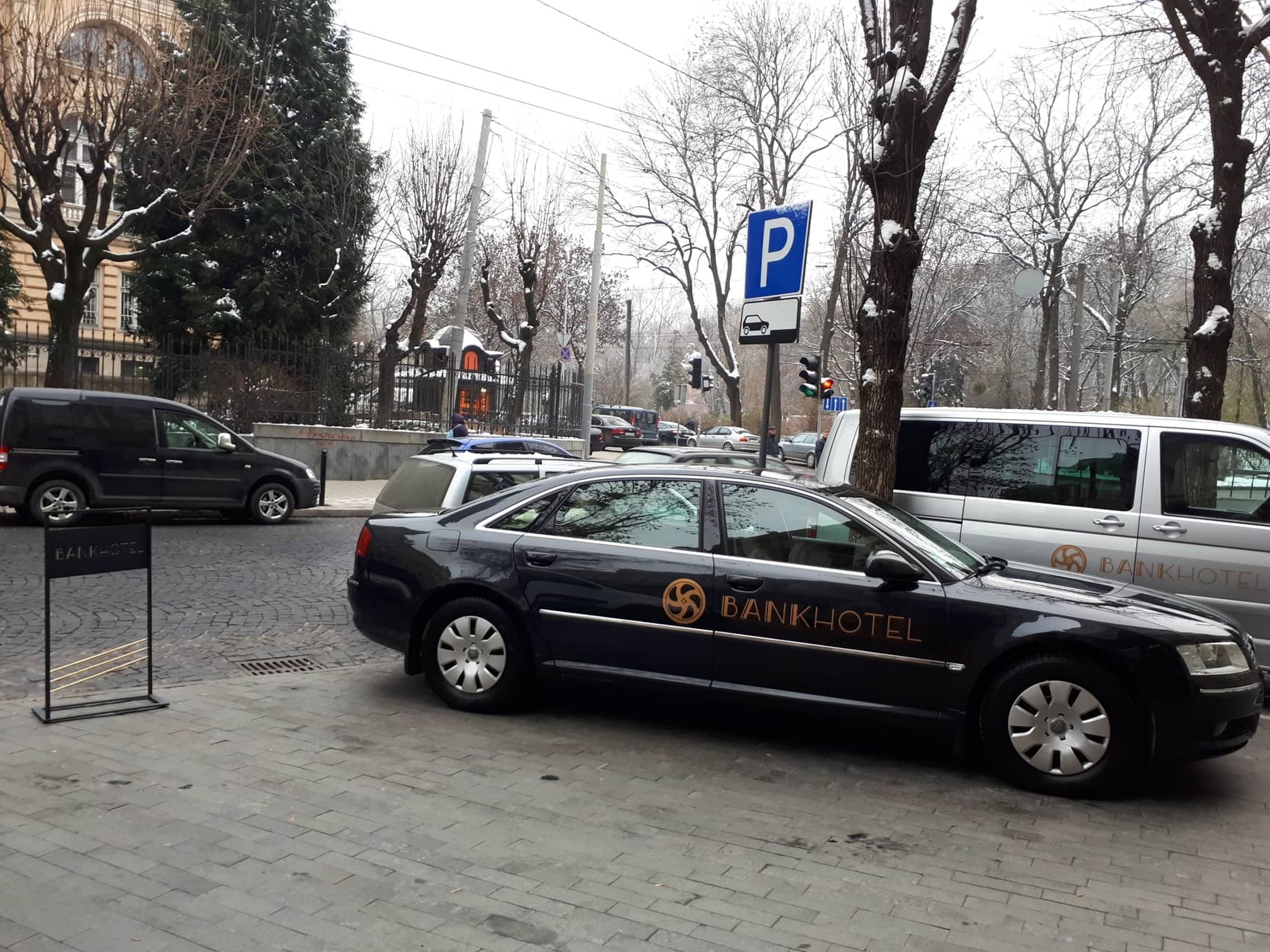 A black car with "BANKHOTEL" branding parked on a city street.