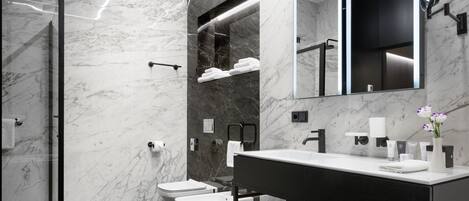 A modern bathroom with a marble wall, a black floor, a white sink, and a large mirror.