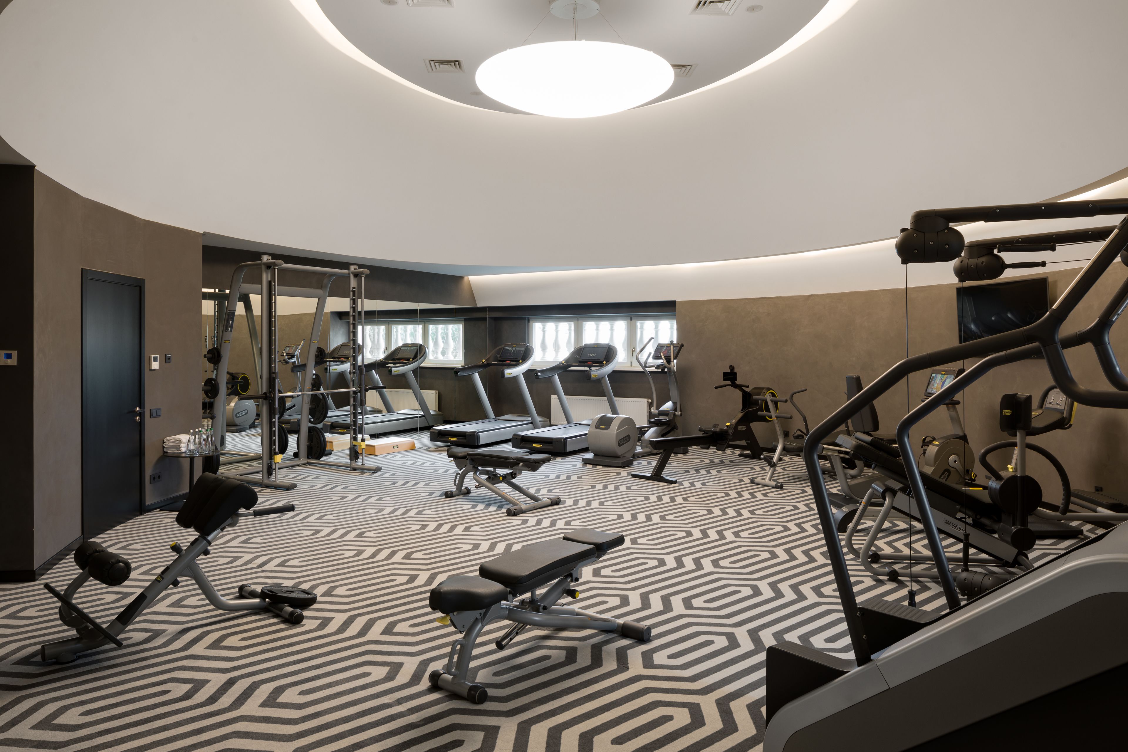 Un gimnasio moderno con cintas de correr, elípticas y equipo de levantamiento de pesas.