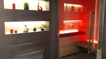 A modern bathroom with a dark tiled floor, a built-in shower with a red light, and shelves with decorative items.