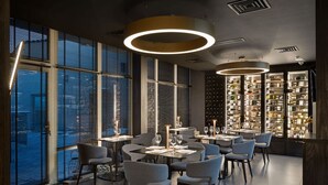 Un restaurante moderno con mesas redondas, sillas y una estantería para vinos.